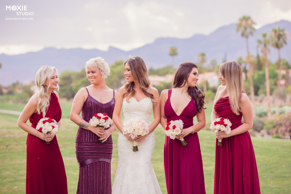 bridesmaids in red dresses with bride on the lawn of a golf course. photo by moxie studio