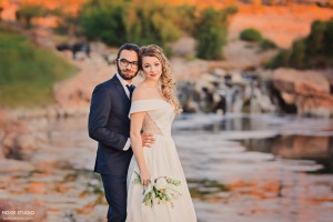 groom in navy suit from friar tux with his lovely bride in front of a waterfall in las vegas