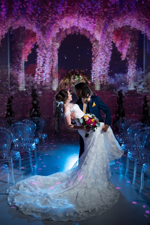 Groom wearing Friar Tux dipping his bride wearing Lovest Bridal Boutique in a romantic gesture. Las Vegas Wedding Photo by LuxLife at Illuminarium