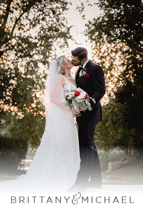 A wedding couple in classic black and white share a kiss in front of the sunset and trees at their Las Vegas wedding