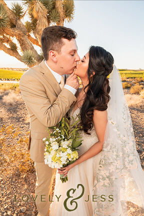 a bride and groom kiss in front of a joshua tree in the desert outside Las Vegas. The bride wears a stunning veil with embroidered flowers.