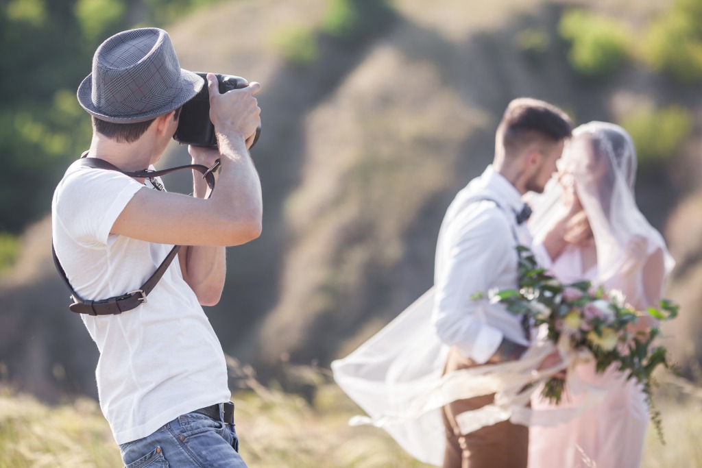 Professional Wedding Photographer captures images of couple at outdoor wedding. Shutterstock_483957421