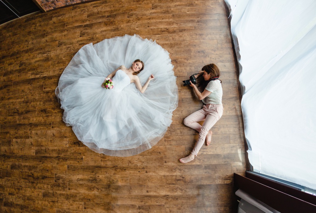 Professional wedding photographer know how to capture the shot. Model lays on ground with wedding dress billowing around for beautiful picture.