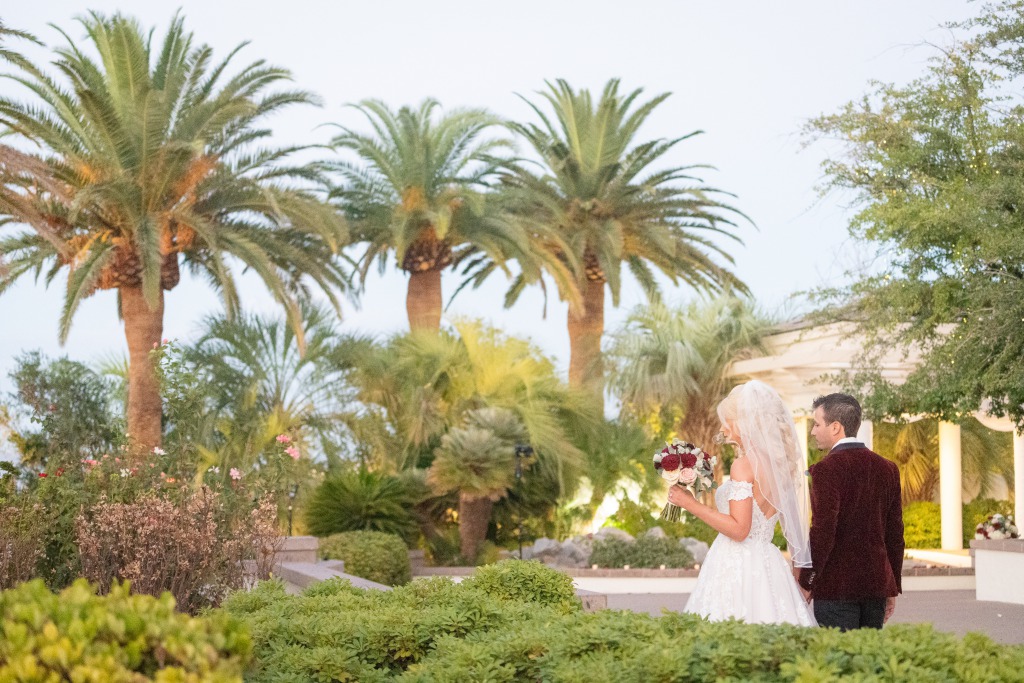 A Bride and groom hold hands and walk around their lushly landscaped outdoor wedding venue in Las Vegas