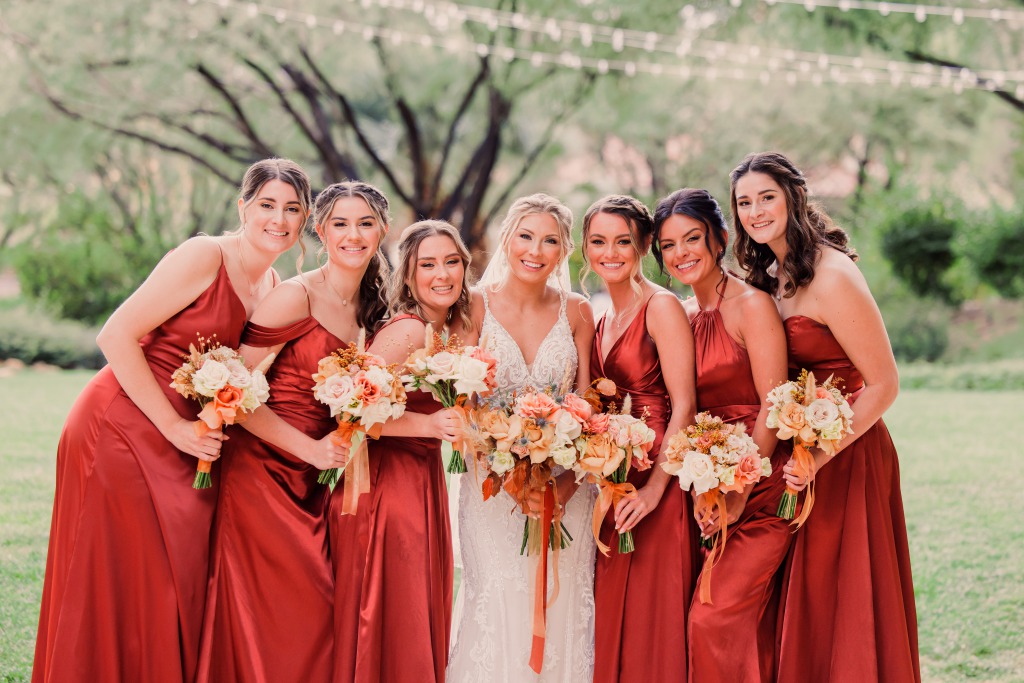 Sunset Wedding Color Inspiration. These bridesmaids are wearing a stunning cinnamon color that looks like it popped right our of a stunning Vegas Sunset. They smile and pose with the bride on their wedding day while holding their flowers at the JW Marriott Resort and Spa in Las Vegas.