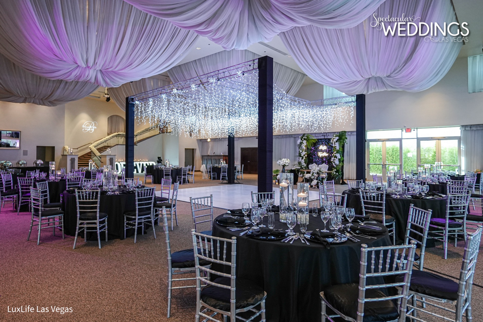What a space to celebrate your nuptials. A canopy twinkling lights over the dance floor are a perfect space for your first dance surrounded by your family seated at tables with black linens.